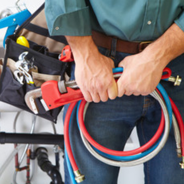 Plumber holding different pipes and plumbing tools