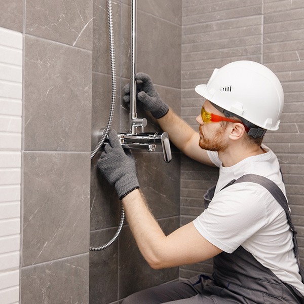 A plumber repairing a shower system as part of a bathroom renovation project in Ottawa, ON