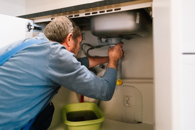 Plumber inspecting and repairing a clogged kitchen sink drain