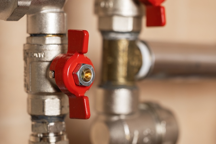 Close-up of red-handled water shut-off valves on plumbing pipes